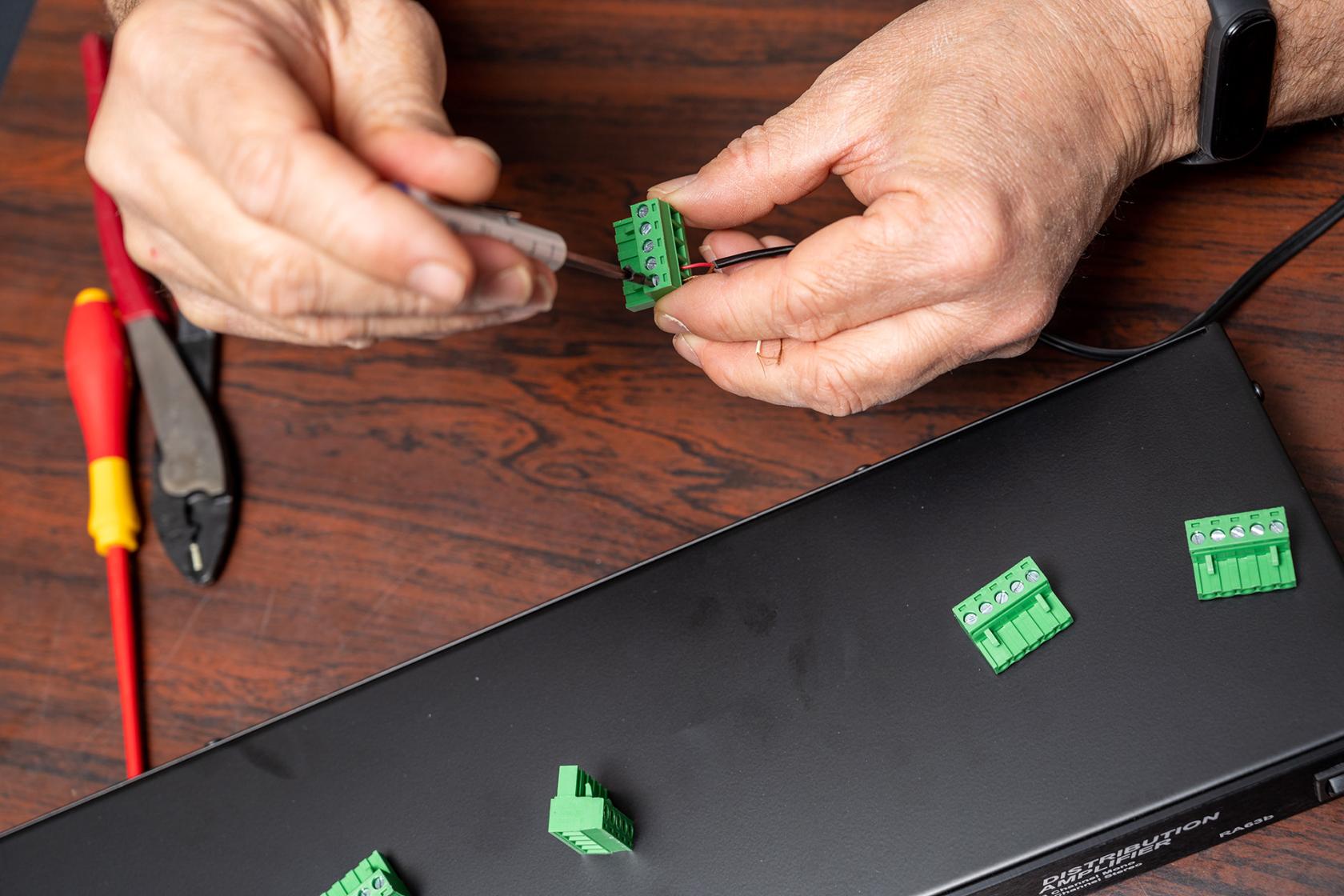 top down photo of two hands working with electrical components