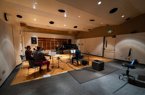 photo of seated people playing instruments in a sound studio